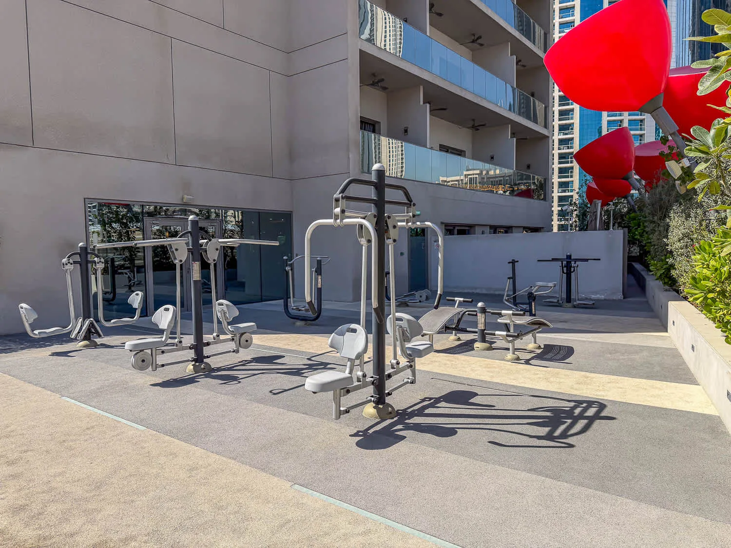 Una zona de ejercicio al aire libre con máquinas junto a un edificio moderno.