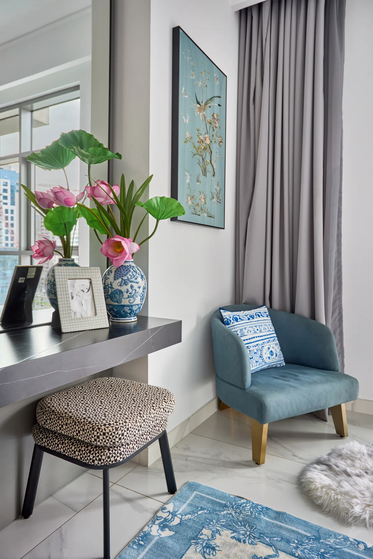 Una zona de estar luminosa con un asiento tapizado, una mesa auxiliar y decoración floral.