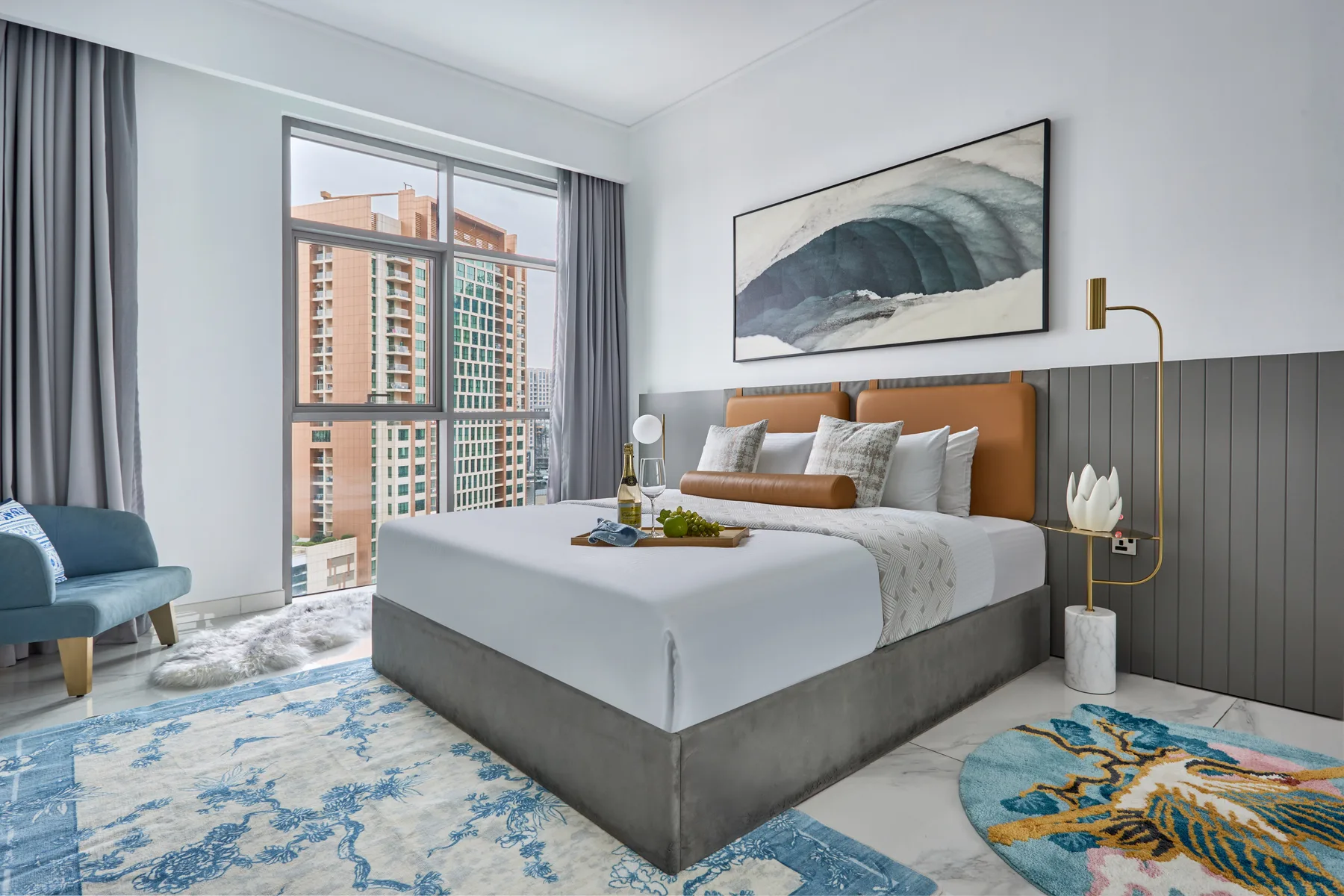 Un dormitorio moderno con una cama grande, una obra enmarcada y una ventana alta.