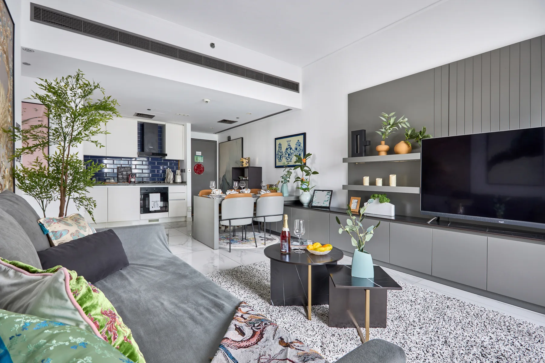 Una sala de estar moderna se abre a la cocina, con asientos y un televisor.