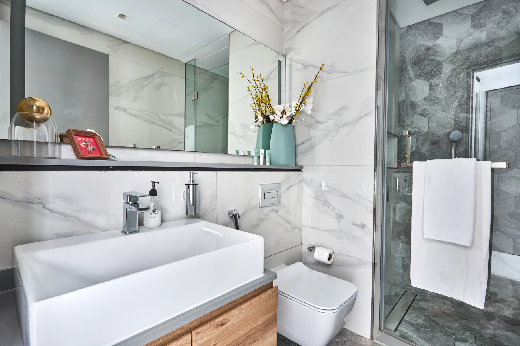 Un baño moderno con un lavabo amplio, espejo de pared y ducha de vidrio.