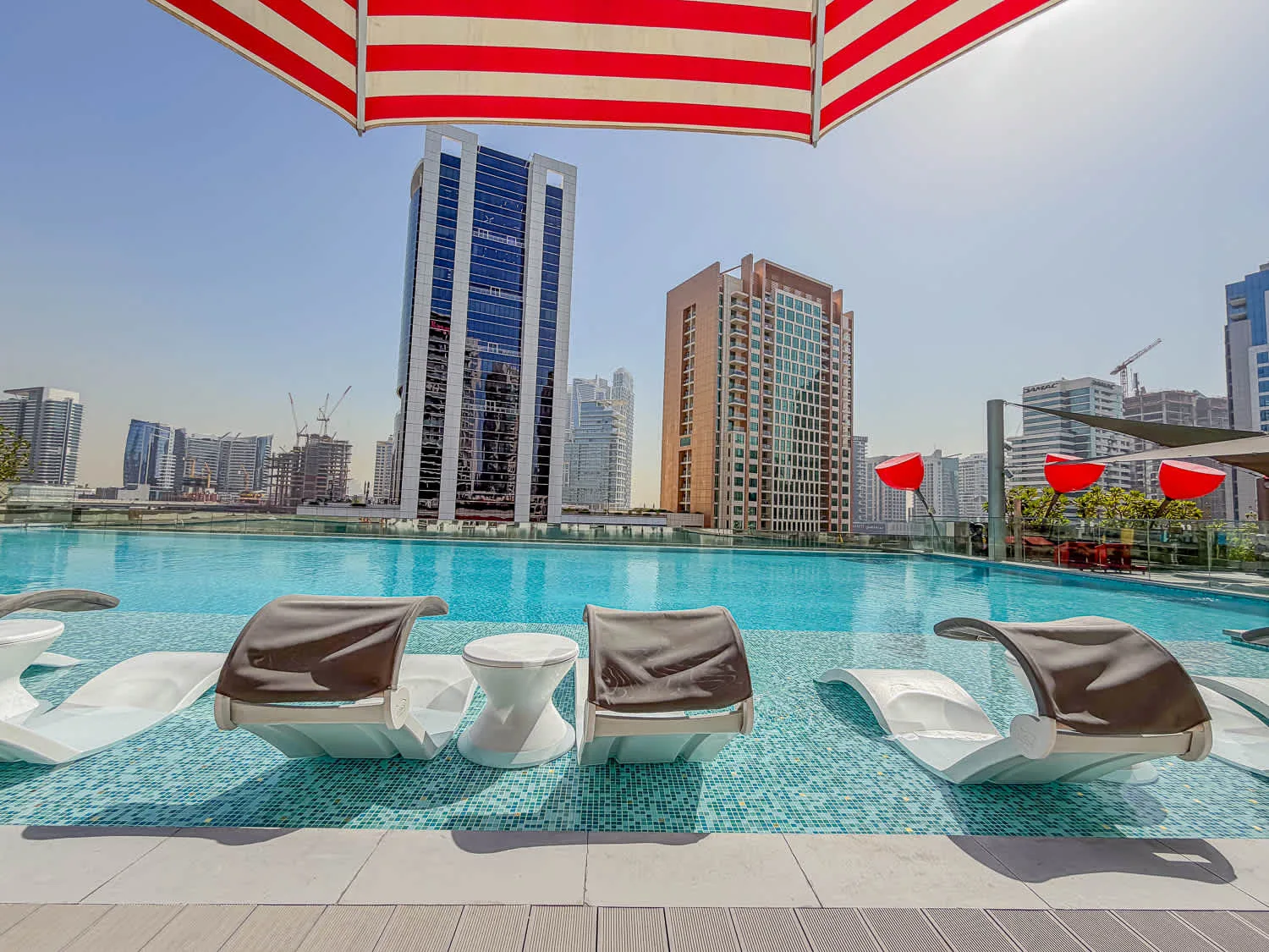 Una piscina en la azotea con asientos sumergidos ofrece vistas del perfil urbano.