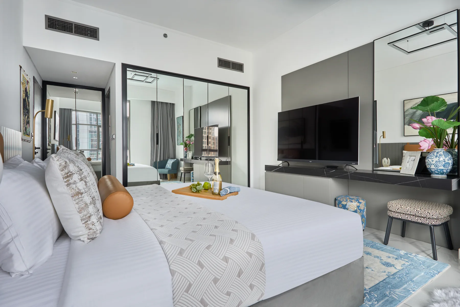 Un dormitorio luminoso con una cama grande frente a un televisor montado en la pared.
