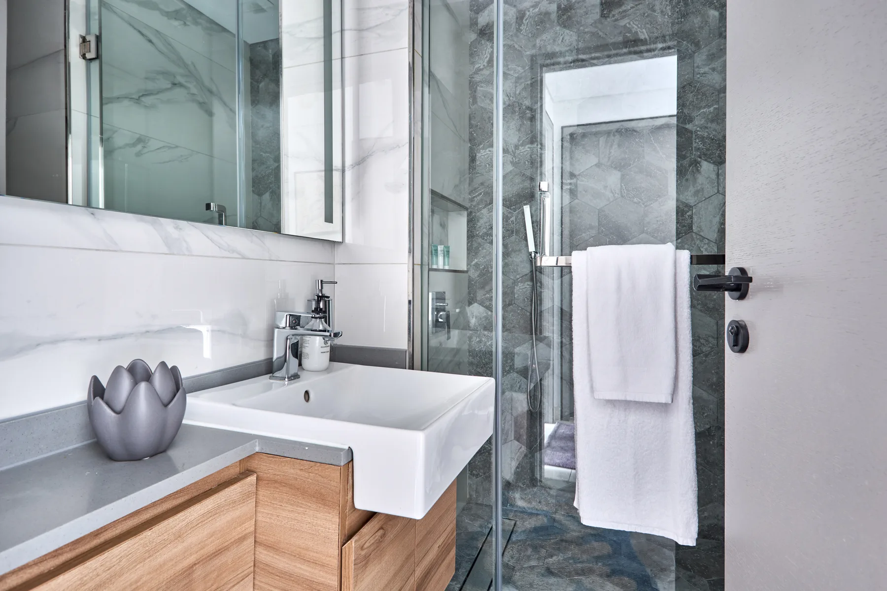 Un baño moderno con un lavabo blanco y una ducha con mampara de vidrio.