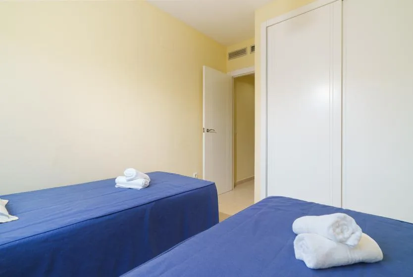 Un dormitorio con dos camas y toallas dobladas.