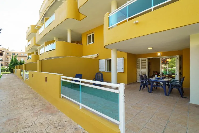 Edificio amarillo con balcones y una zona de estar al aire libre.