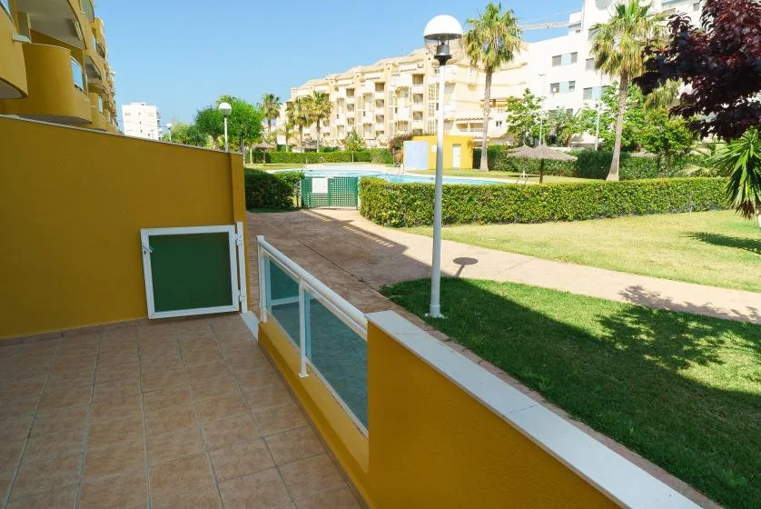 Una terraza embaldosada da a un césped ajardinado y edificios de apartamentos.