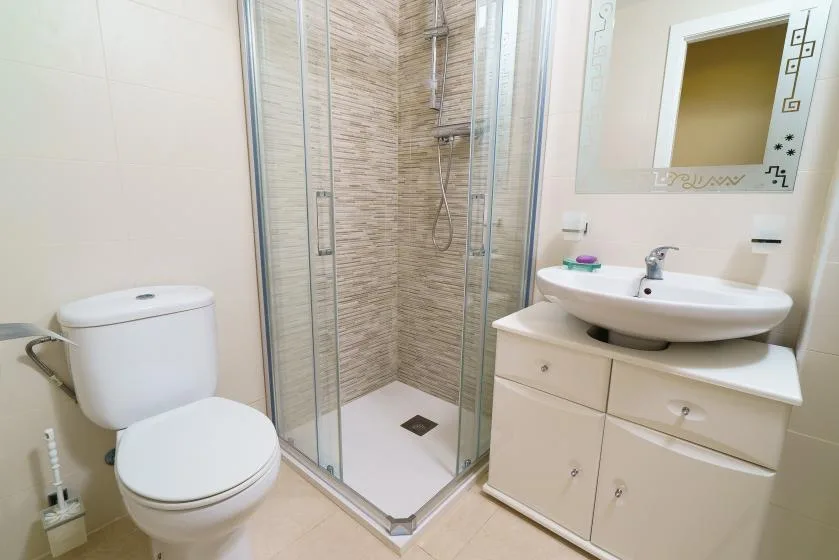 Un baño con ducha de vidrio, inodoro y lavabo con mueble.