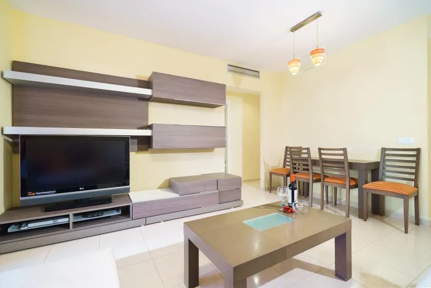 Una sala de estar y comedor con televisor, mesa de centro y comedor.