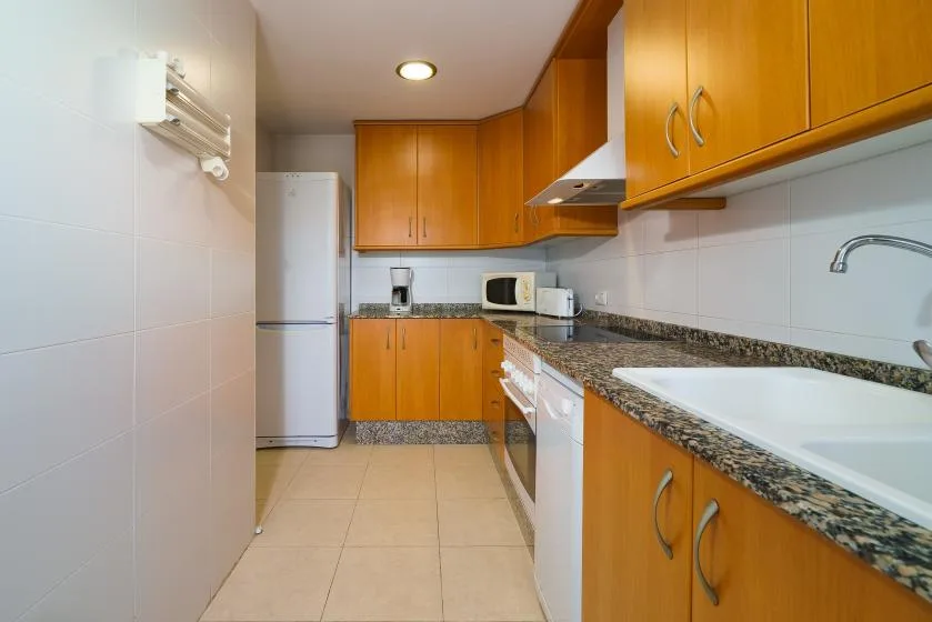Una cocina alargada con gabinetes de madera, una encimera y un fregadero.