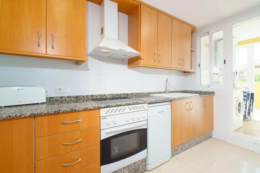Una cocina luminosa con armarios de madera y una encimera.