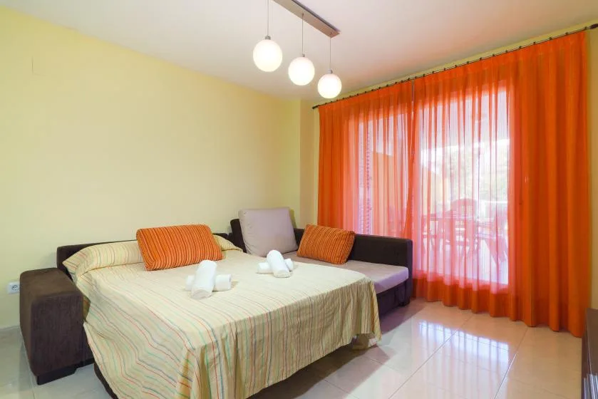 Un dormitorio con una cama y asientos junto a cortinas naranjas.