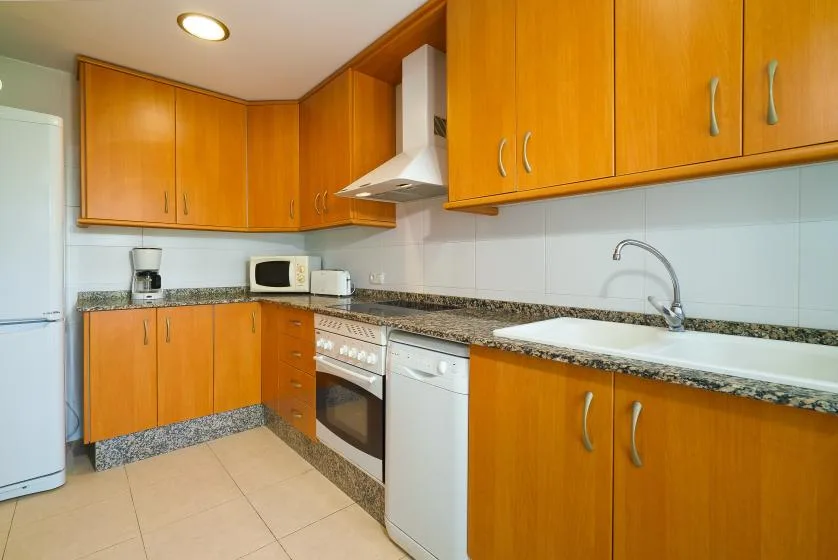 Una cocina con muebles naranjas, una encimera y un fregadero.