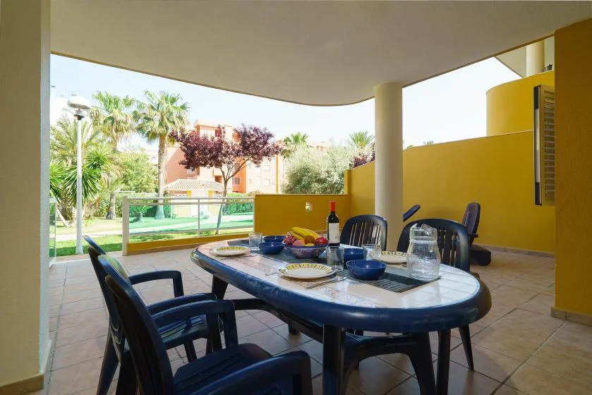 Una zona de comedor exterior cubierta con una mesa junto a un jardín.