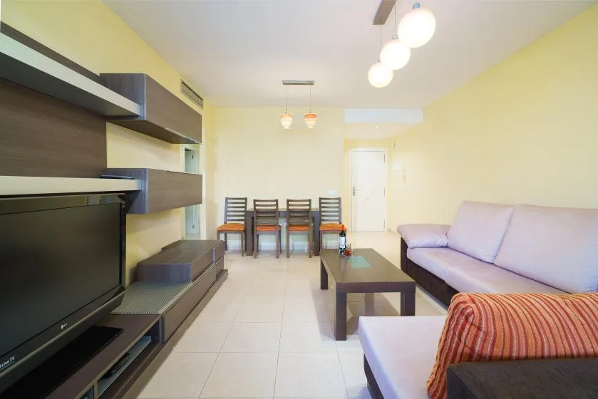Una sala de estar y comedor con asientos, un televisor y una mesa de comedor.