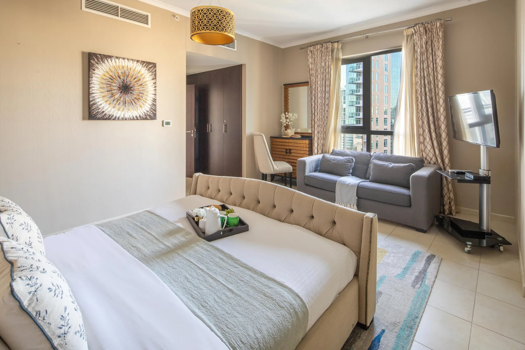 Dormitorio con zona de estar, cama, sofá y ventanas amplias.