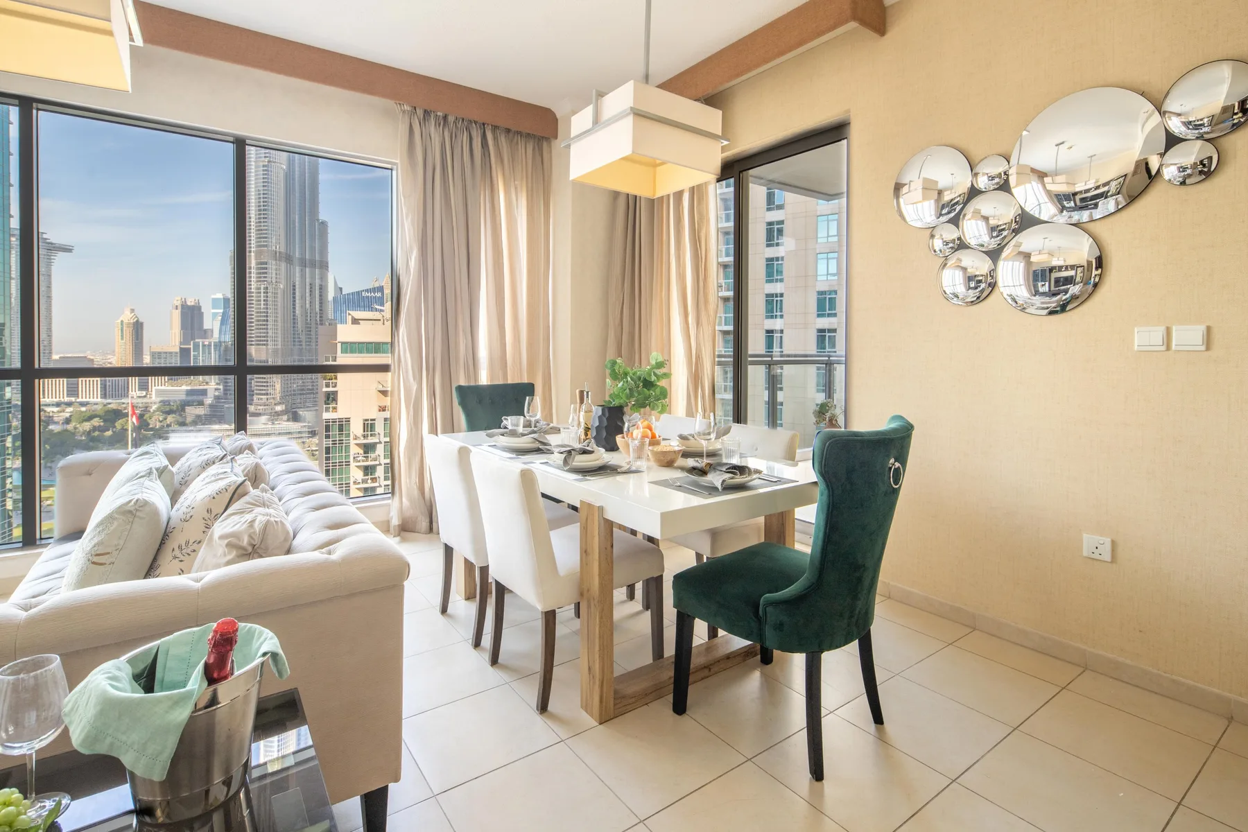 Un comedor con mesa y sillas junto a una sala de estar y grandes ventanas.