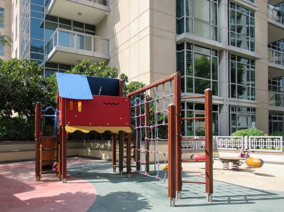 Un parque infantil al aire libre con una estructura colorida para trepar junto a un edificio moderno.