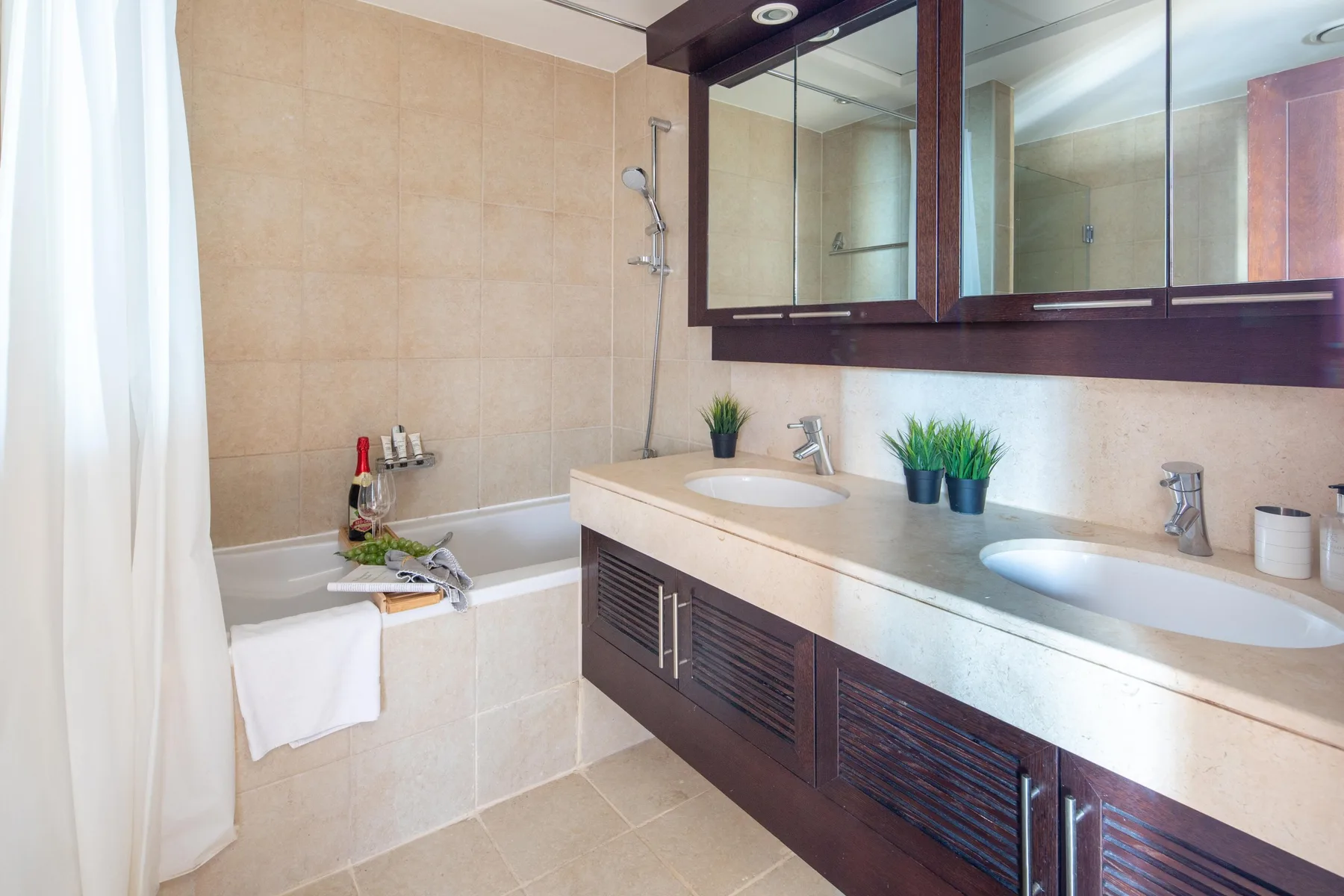 Un baño con bañera, ducha y un largo tocador con dos lavabos.