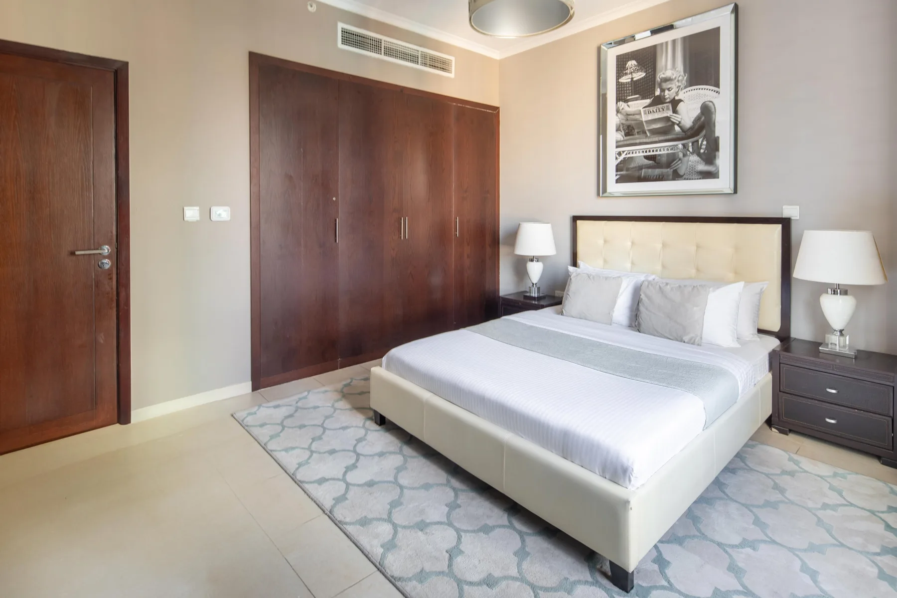 Un dormitorio con una cama grande, mesitas de noche y una alfombra estampada.