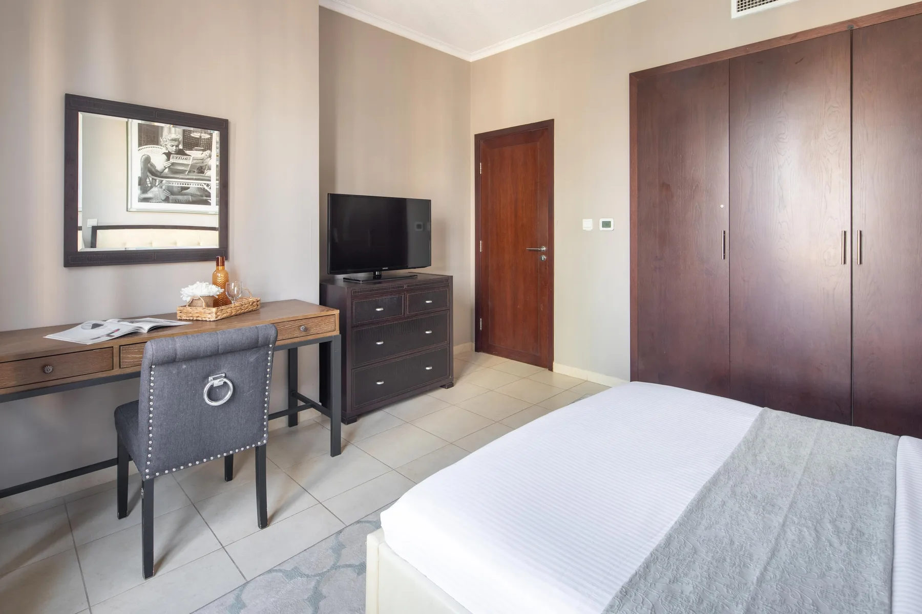 Un dormitorio con una cama, un escritorio y un armario grande.