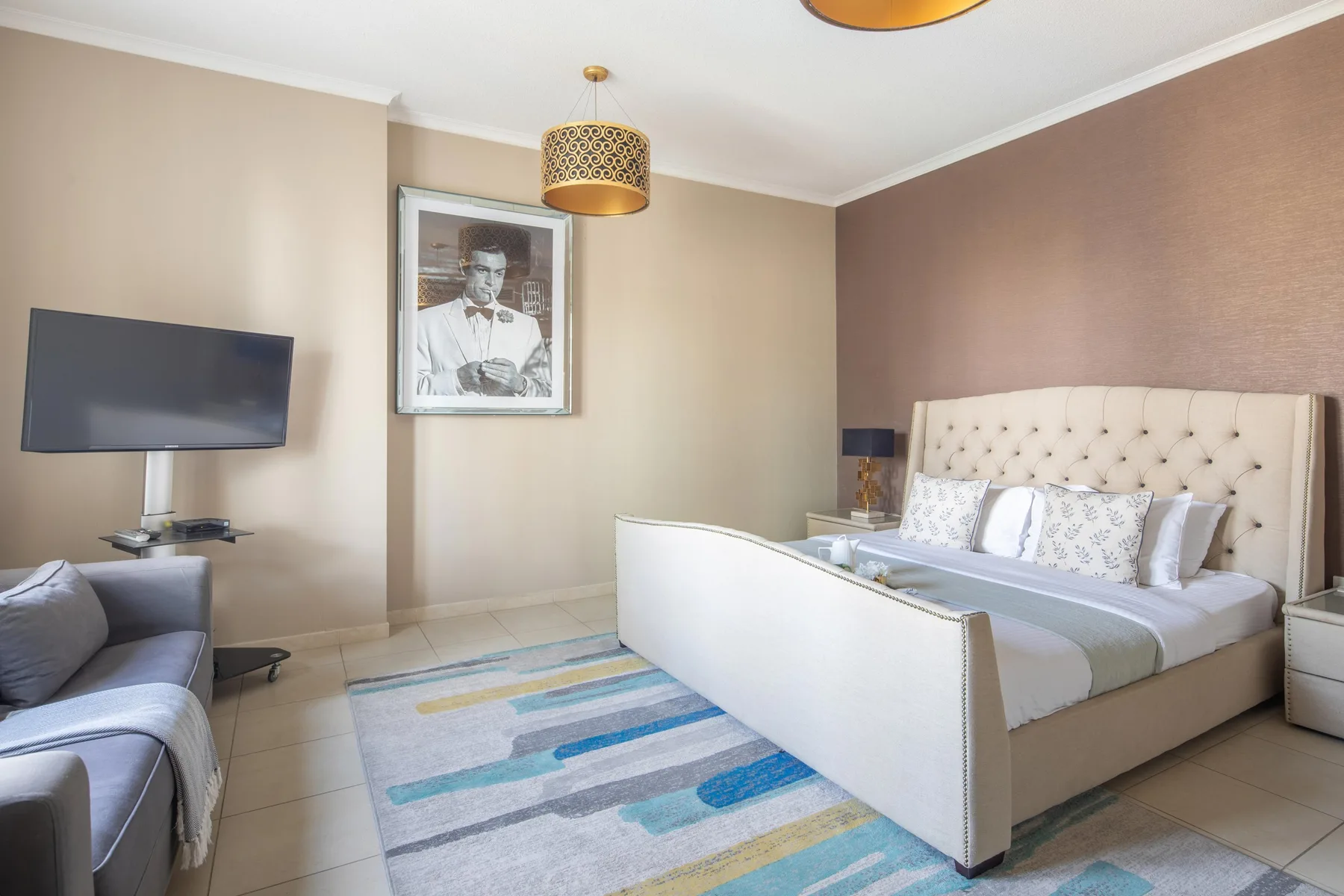 Un dormitorio con una cama grande, un televisor montado en la pared y una alfombra a rayas.
