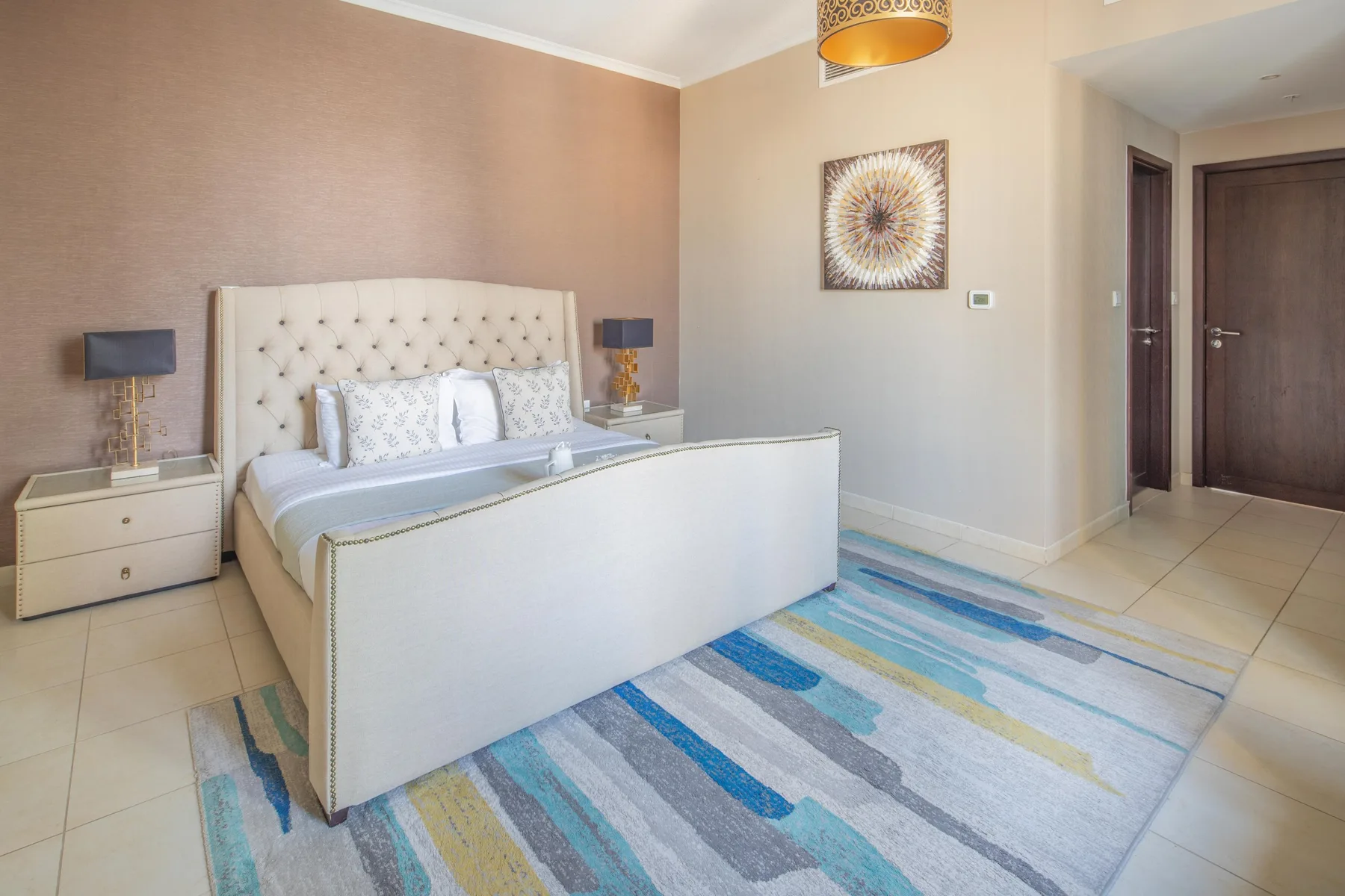 Un dormitorio con una cama, mesas de noche y una alfombra estampada.