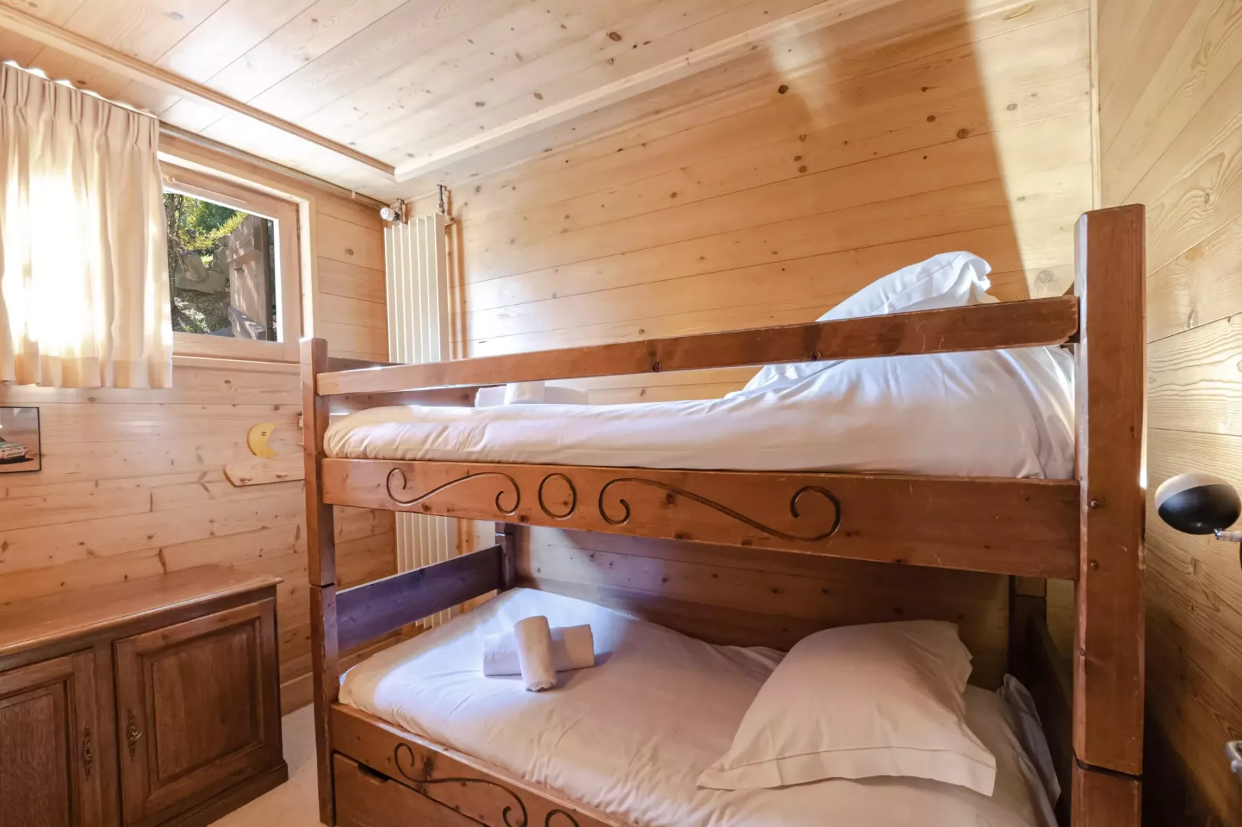 A wooden bunk bed with white bedding in a wood-paneled bedroom.