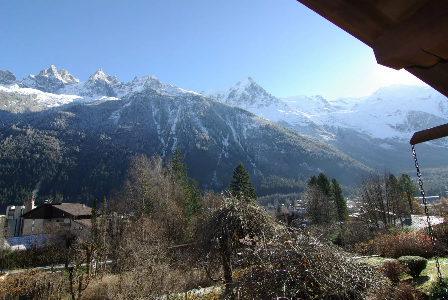 A mountain landscape with snow-covered peaks rising above a wooded valley.