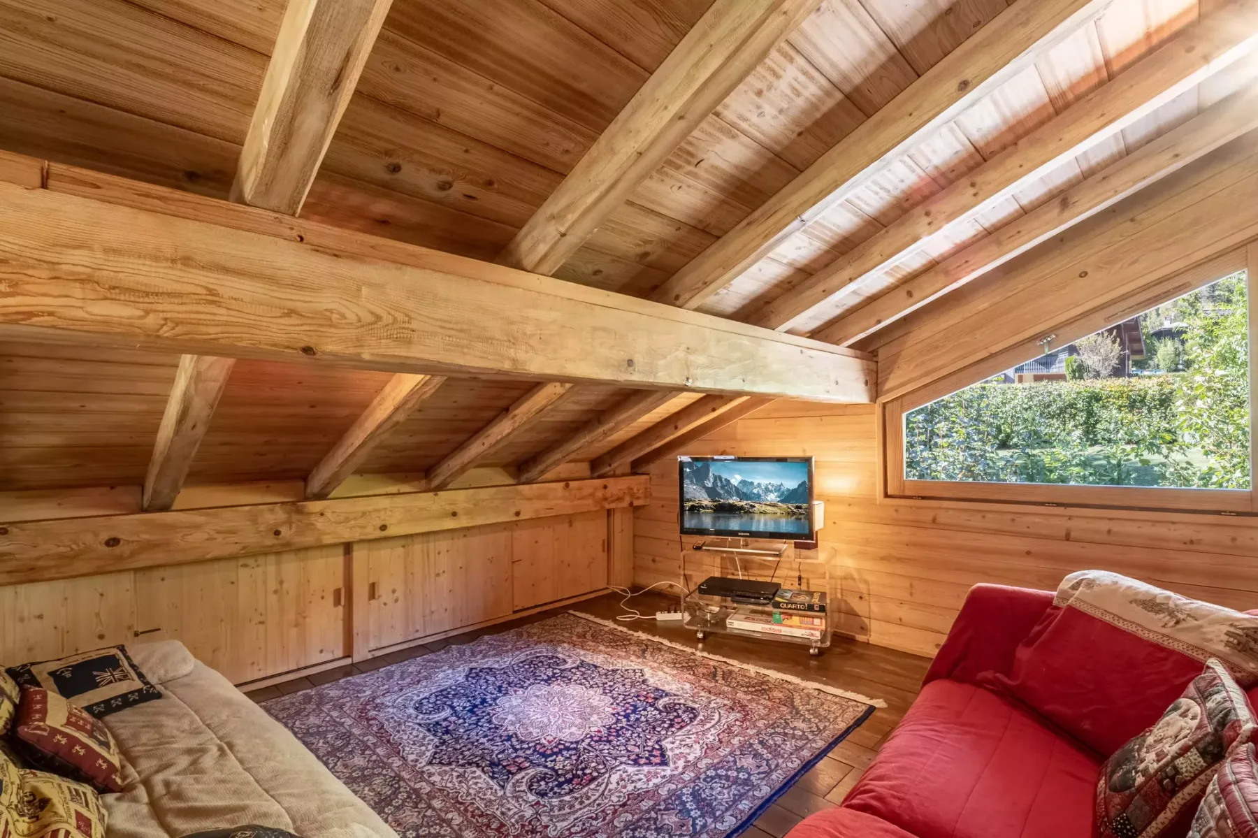 A wood-paneled living room with seating around a patterned rug.