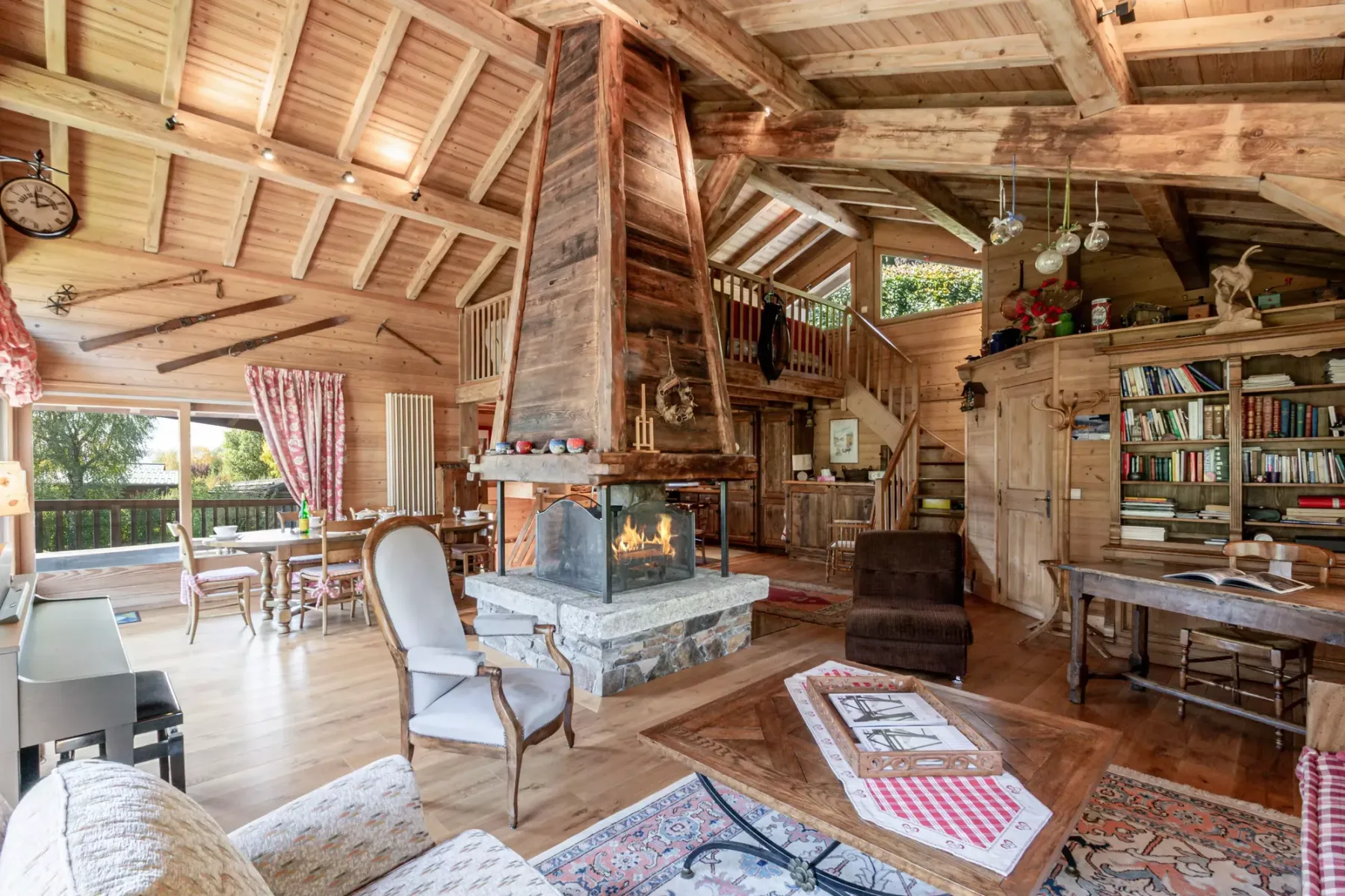 A rustic living room with a stone fireplace, wooden beams, and seating.