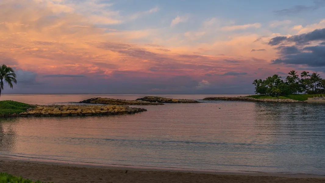 Una tranquila laguna costera refleja un cielo colorido al atardecer.