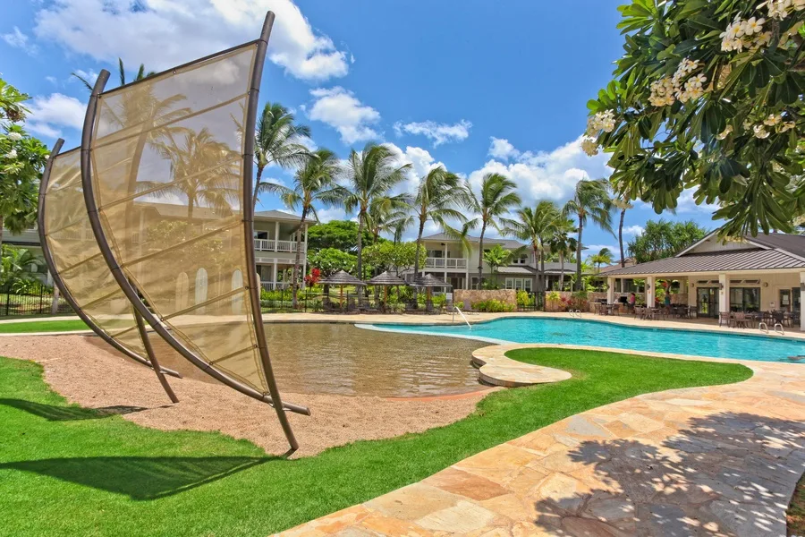 Zona de piscina con una sección poco profunda y palmeras.