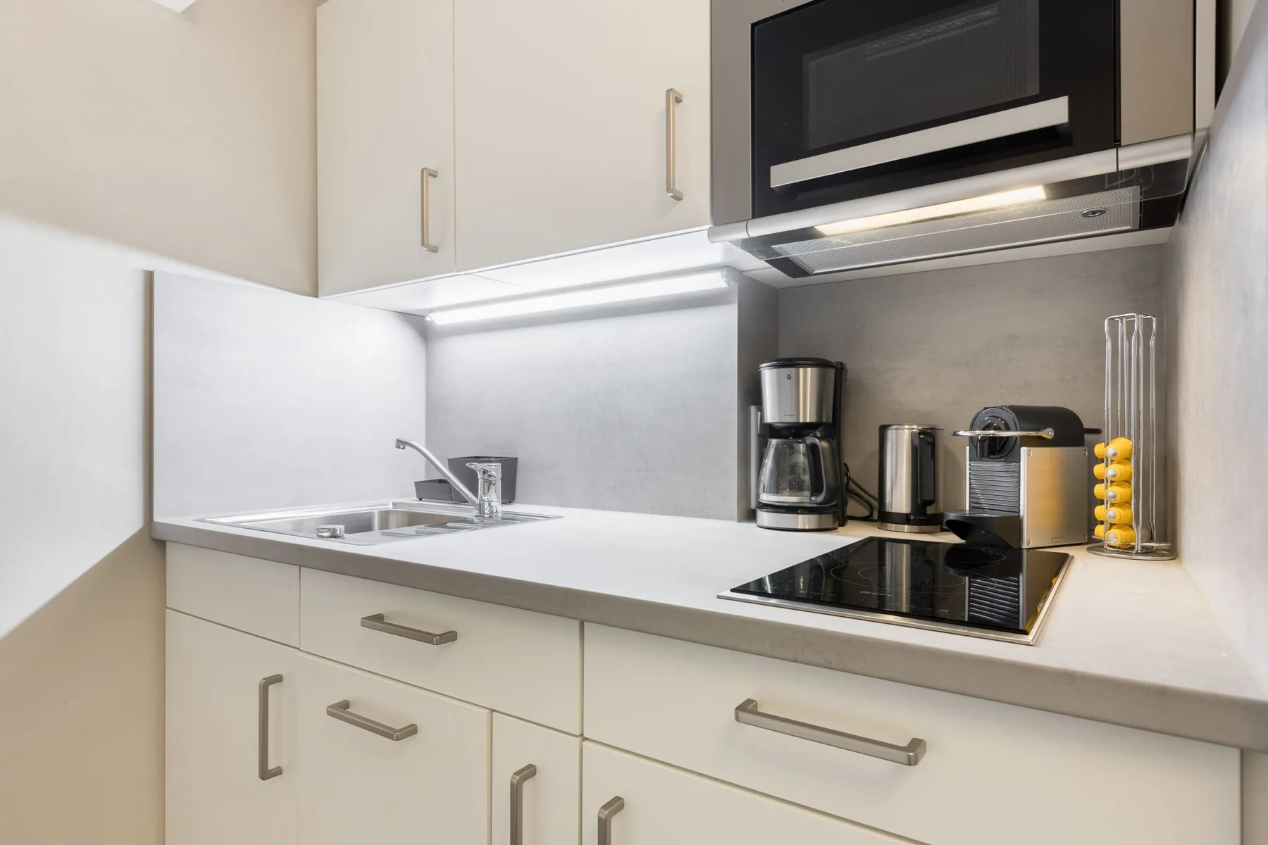 A modern kitchen with a sink, countertop, and built-in cooktop.