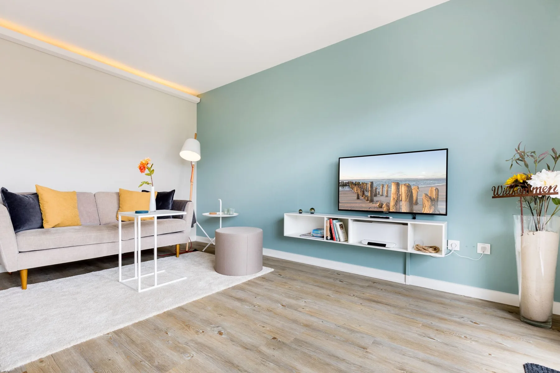 A living room with seating, a television, and a low white media console.