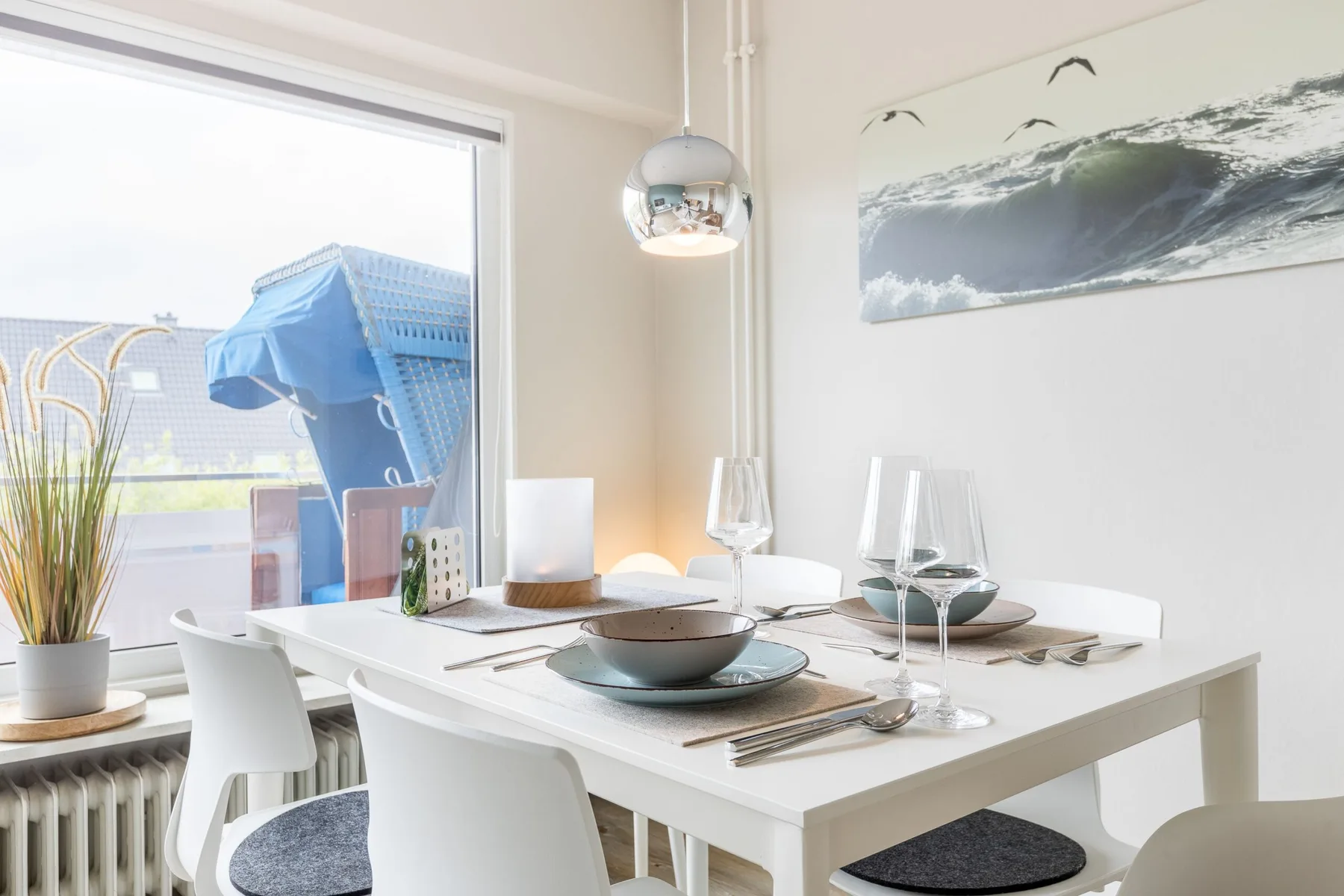 A bright dining area with a white table set beside a large window.