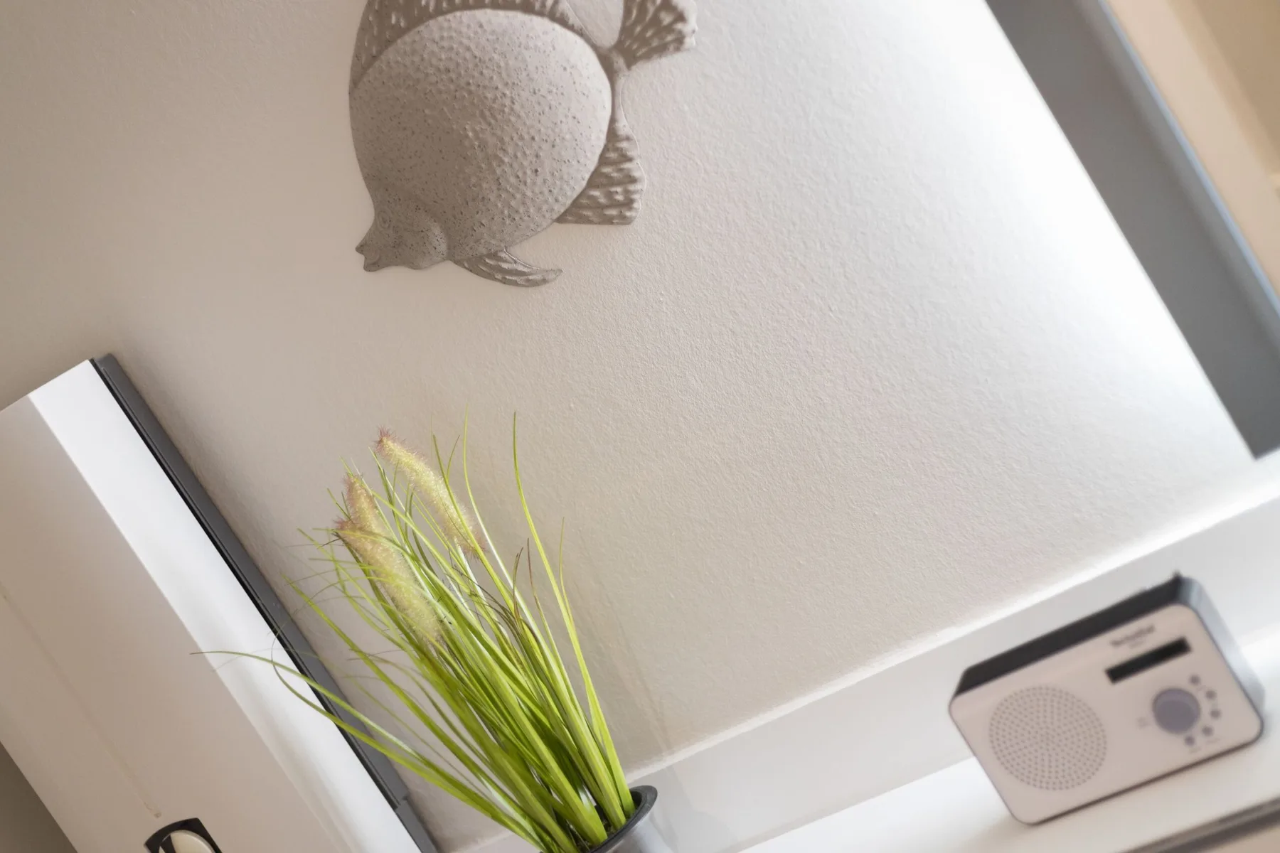 A bright interior corner features a small radio and decorative wall art.