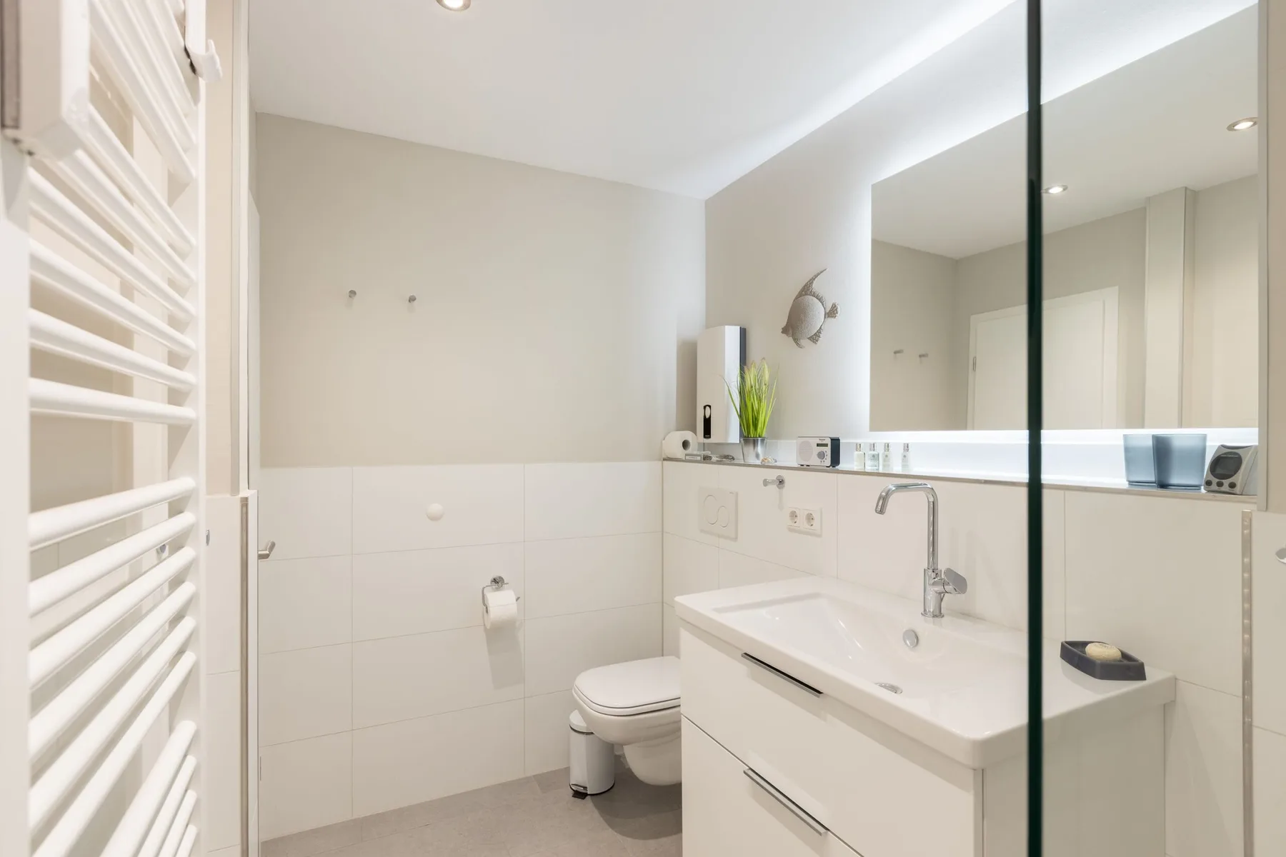 A bright bathroom with a sink, toilet, and large mirror.