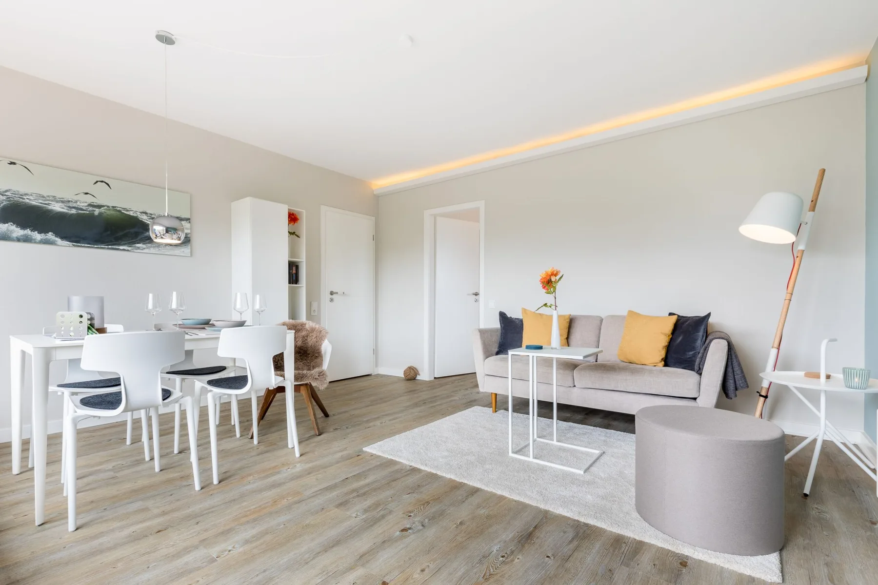 A bright living and dining area with seating, a dining table, and a floor lamp.