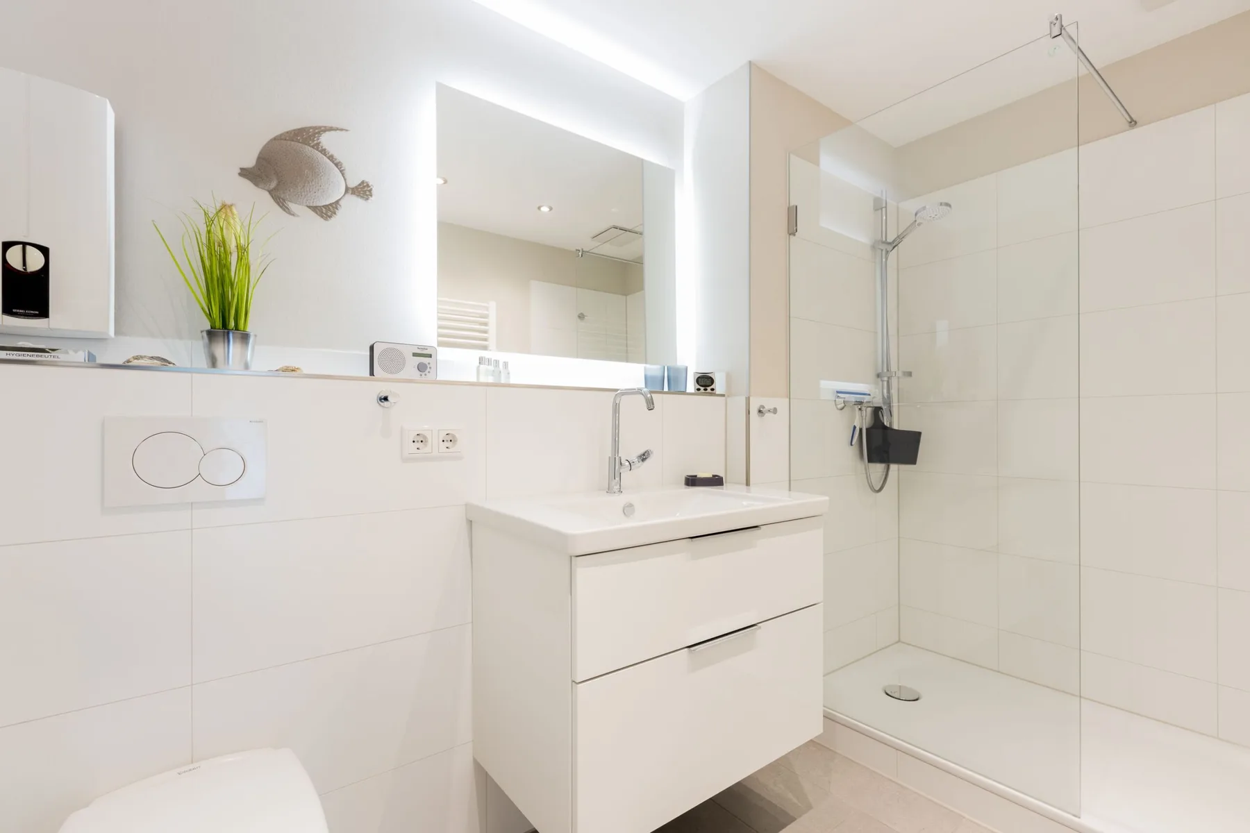 A bright bathroom with a vanity, mirror, and glass shower.