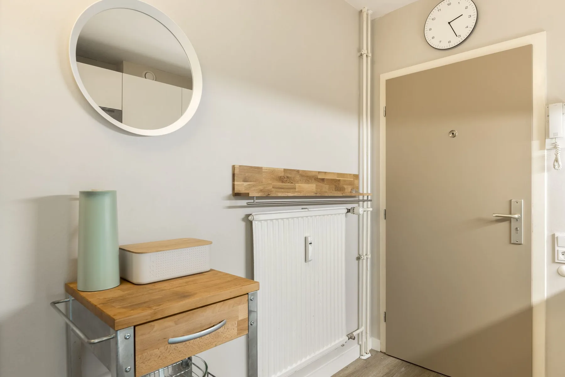 An interior hallway with a wooden-topped console beside a radiator and closed door.