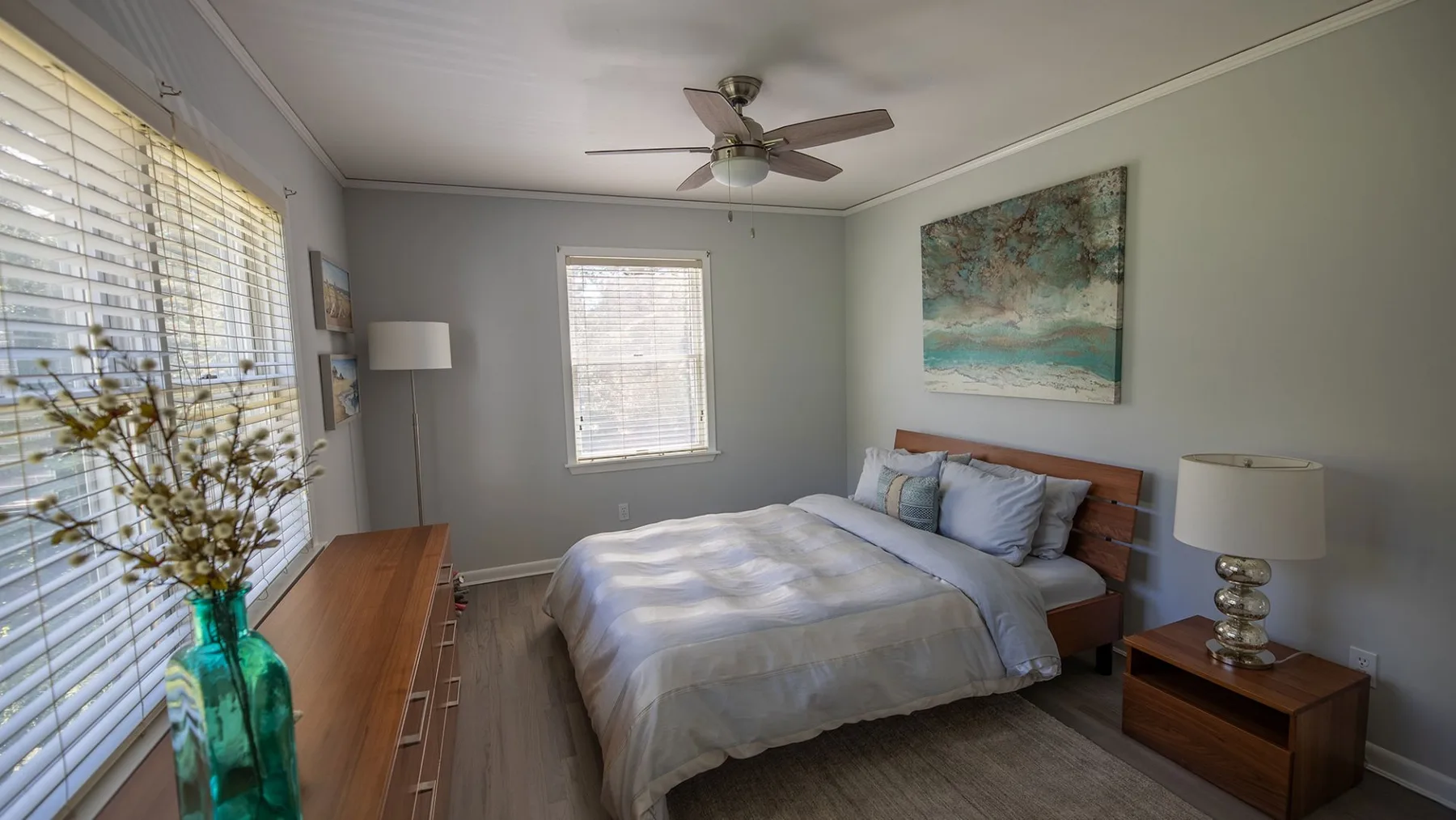 A bedroom with a bed, bedside table, and artwork on the wall.