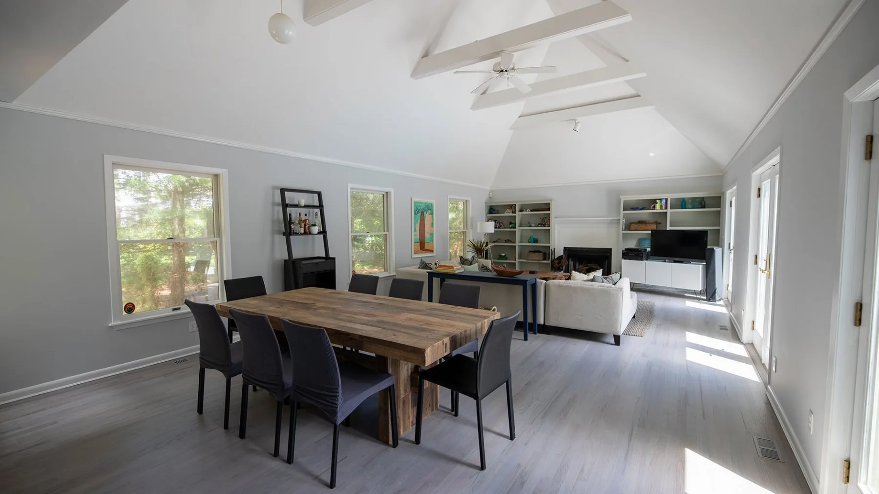 A bright open living and dining room with a wooden dining table and seating.