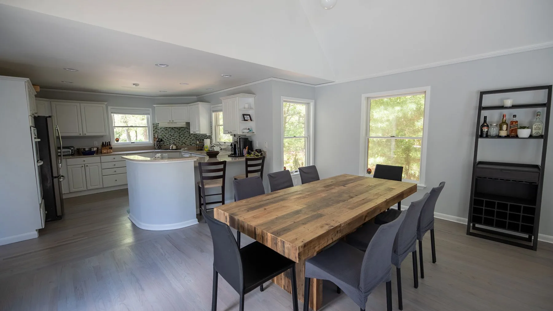 An open dining area with a wooden table and kitchen beyond.