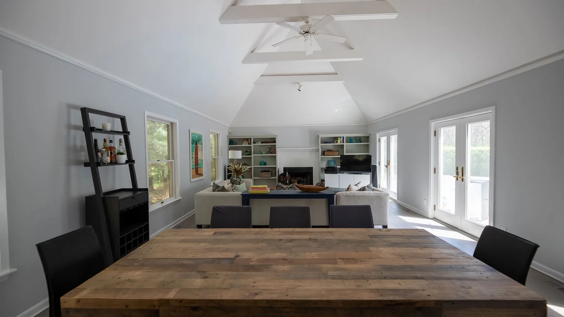 A bright open living room with a large wooden table and seating.