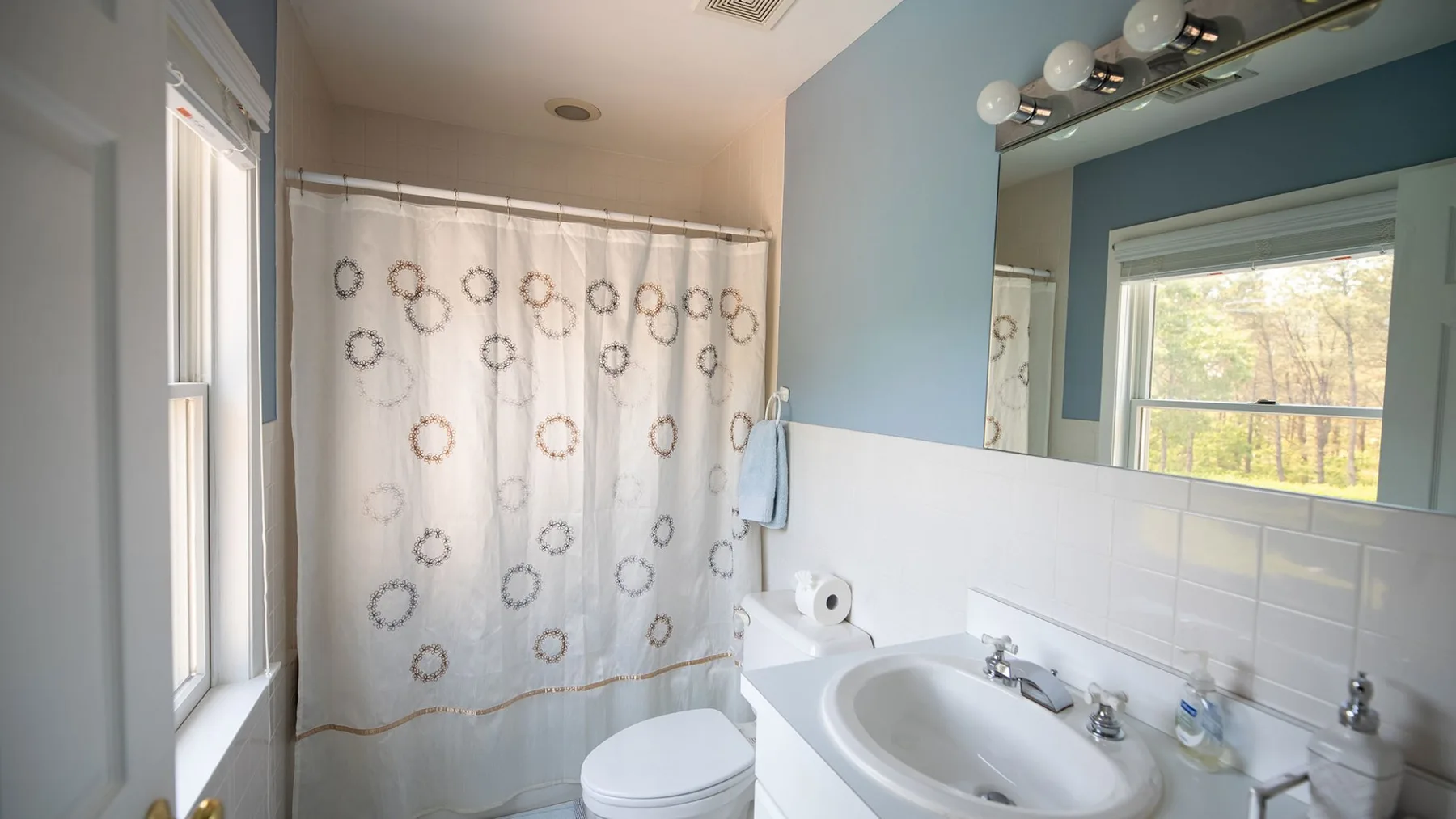 A bathroom with a shower curtain, toilet, and sink.