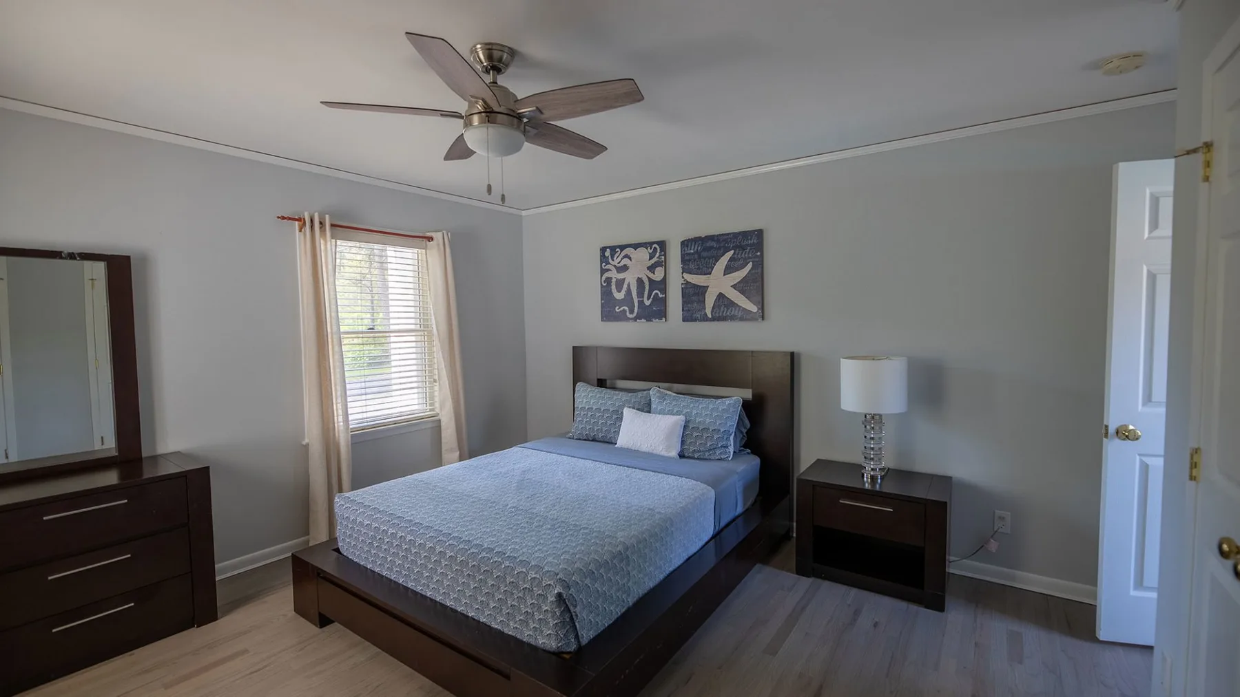 A bedroom with a bed, bedside table, and ceiling fan.