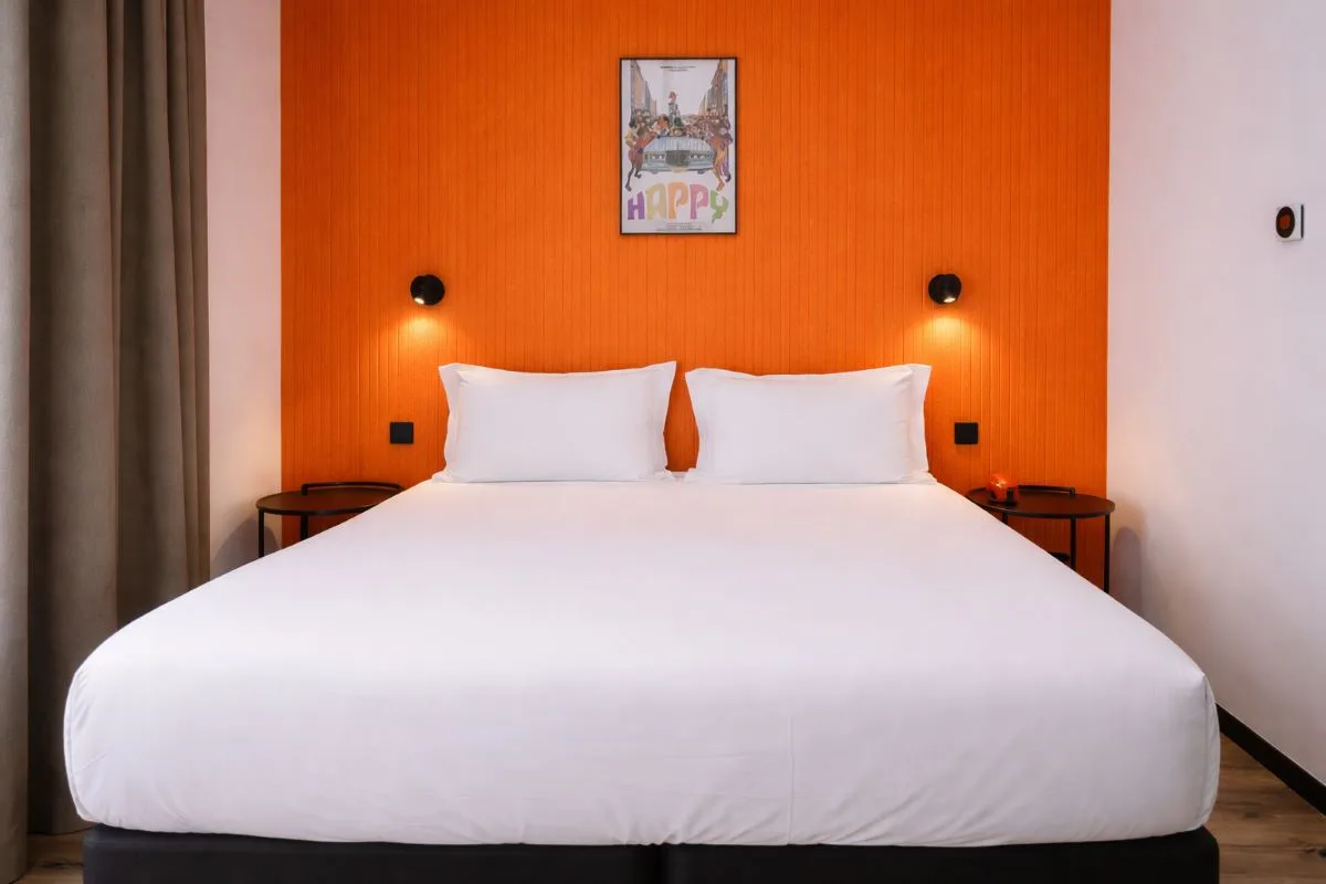 Habitación doble con cabecero naranja y cuadros en la pared