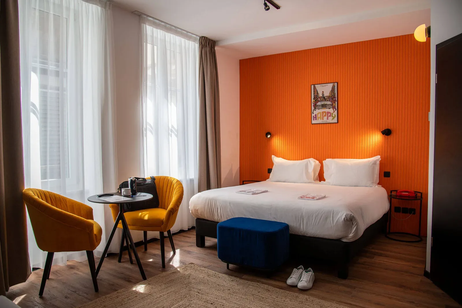Habitación doble con pared naranja y sillones amarillos