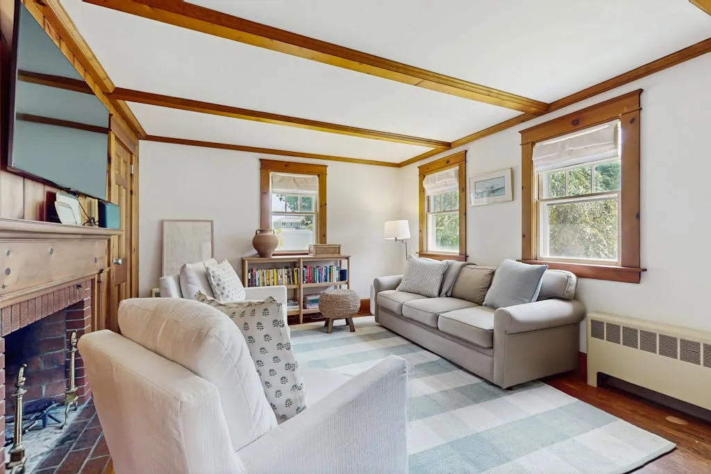 A bright living room with seating, a fireplace, and large windows.